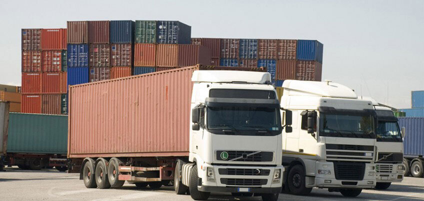 کامیونها و ماشینهای سنگین کنار هم در جاده یا پارکینگ، نشاندهنده افزایش کرایه حمل و نقل.